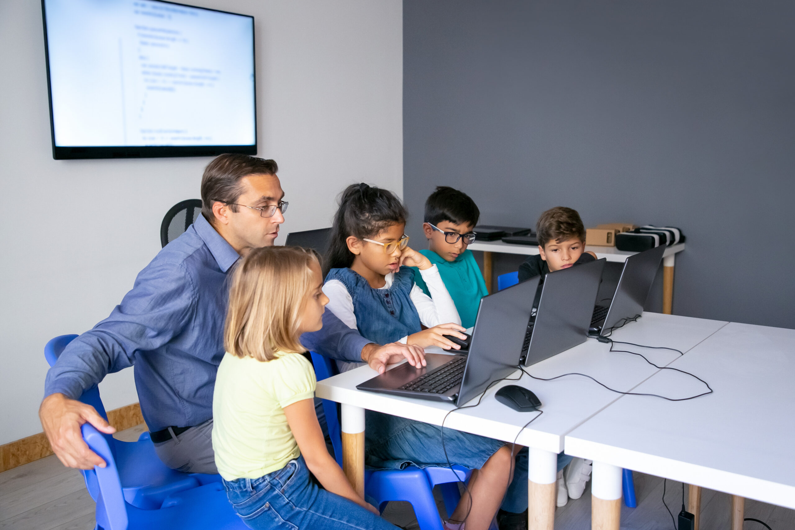Multiethnic pupils doing task with help of teacher