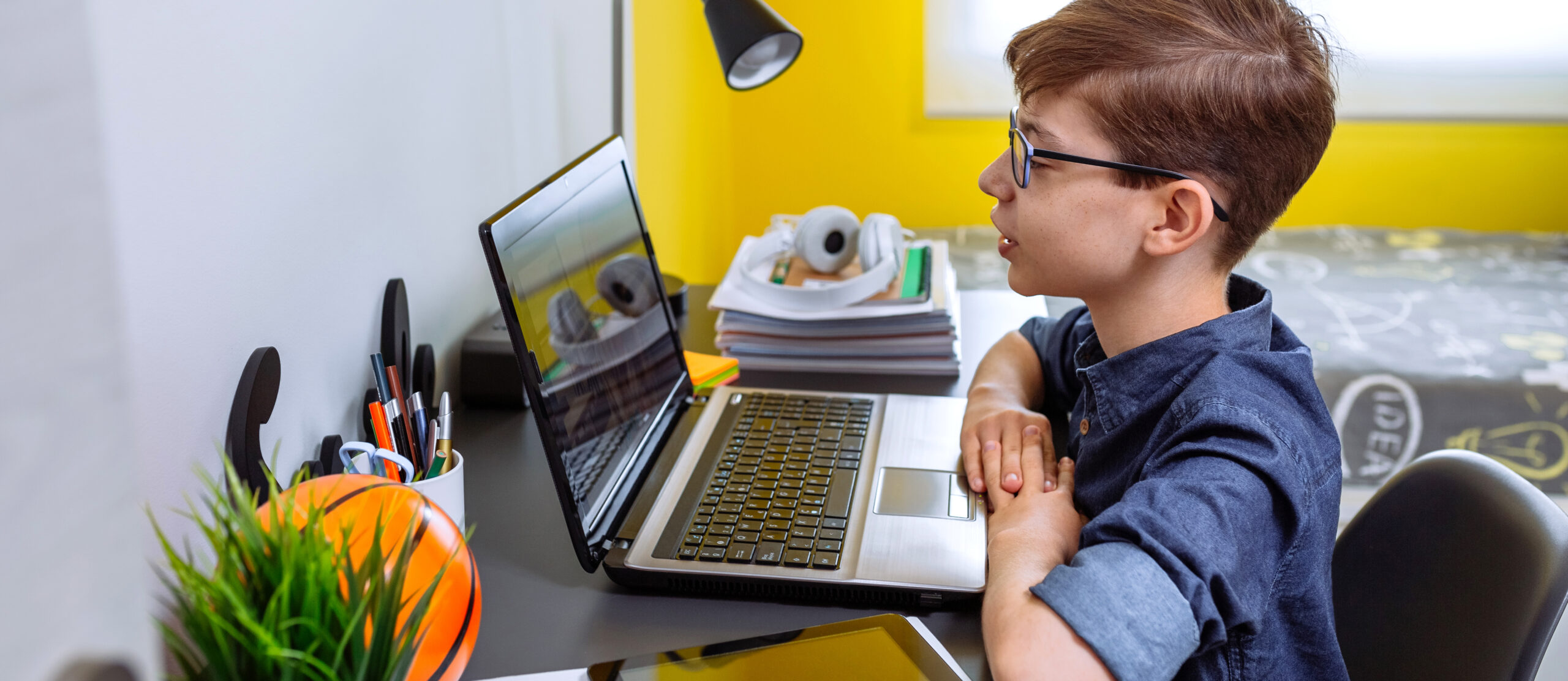 Preteen receiving class at home with laptop from his bedroom. Home schooling concept